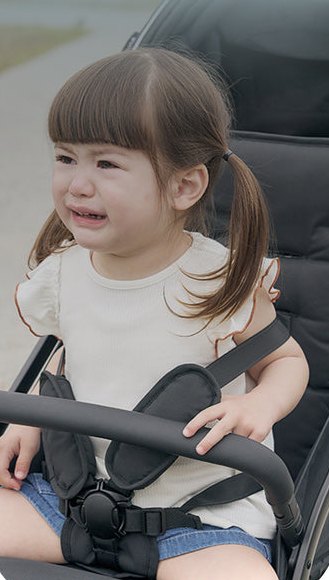 在手推車裡哭鬧的幼兒